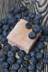 Blueberries are scattered on pine boards. Portion marshmallow. Close-up shot.