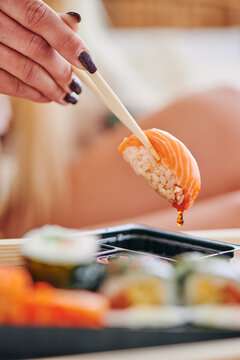 Woman eats sushi with salmon. Sushi with salmon dipped in soy sauce close-up. High quality photo
