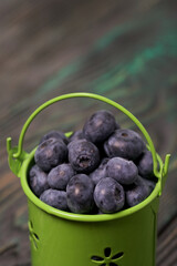 Blueberries in a metal bucket. On pine boards. Close-up shot.