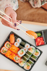 Young woman eating sushi at home. Home food delivery concept. Japan food. Top view. Space for text. High quality photo