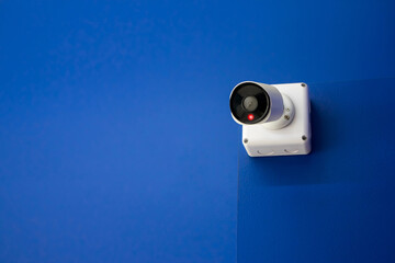 CCTV camera on blue concrete wall to record private or public spaces White Close Circuit Television...