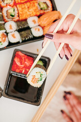 Young woman eating sushi at home. Home food delivery concept. Japan food. Top view. Space for text. High quality photo