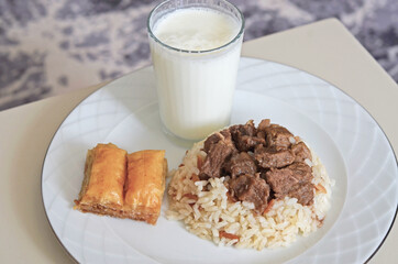 A traditional Kurban Bayram meal in Turkey. Braised meat served with rice, Baklava and Ayran drink.