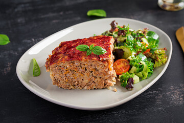 Slice of casserole with rice, minced beef meat and cabbage with tomatoes sauce on top decorated with basil on the plate