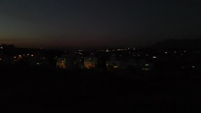 silhouette of mountain biker at sunset with city lights on parallax background