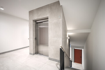 Staircase of modern apartment building. White walls with marble decorations. Metalic railings and tile floor. Clean look.