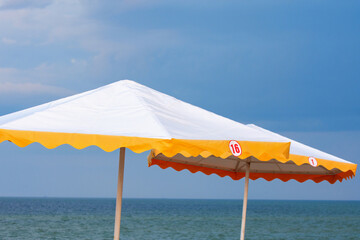 Sun umbrellas on the beach. The sky is stormy, there are no people.