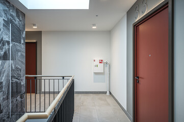 Staircase of modern apartment building. White walls with marble decorations. Metalic railings and tile floor. Clean look.