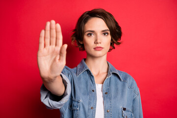Photo of strict brunette millennial lady hand stop wear jeans shirt isolated on red color background - obrazy, fototapety, plakaty
