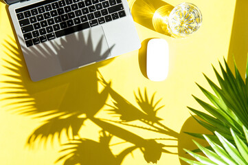 Trendy summer office workplace flat lay. Laptop sun shadow