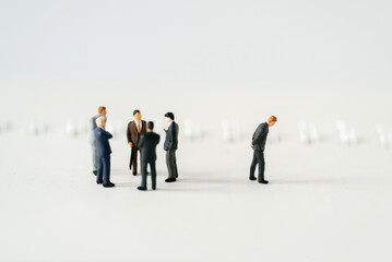 Fototapeta premium Miniature people A depressed Businessman mini figures standing out of group thinking on white background using as Success Business partnership development and Commerce Strategy Planning concepts