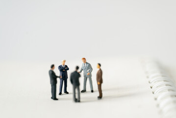 Miniature businessman planning thinking success deal business on white background using as commitment, insurance agreement, travel investment and partnership business development joint venture concept