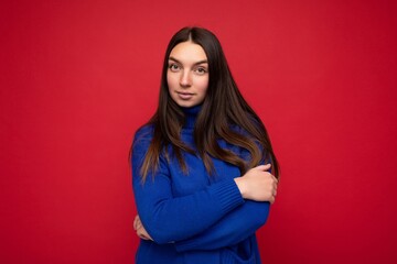 Young calm self-confident serious beautiful brunette woman with sincere emotions isolated on background wall with copy space wearing casual trendy blue sweater. Emotions concept