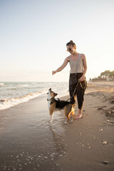 young woman with a beagle dog having fun by the sea