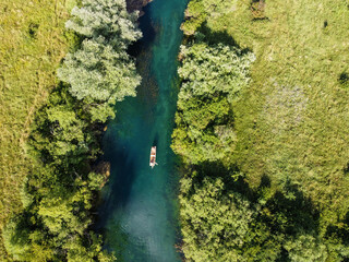 Aerial drone view of young man floats rowing boat on the river. People kayaking on the water in...