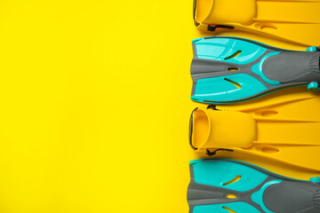 Different flippers on yellow background, flat lay. Space for text © New Africa