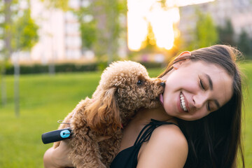 Two best friends. Beautiful girl and her pet, little golden poodle dog strolling in public park, outdoors. Summer time. Sincere emotions. leisure activities concept