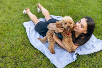 Two best friends. Beautiful girl and her pet, little golden poodle dog strolling in public park,...