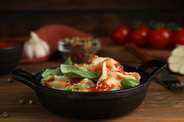 Tasty ravioli with tomato sauce served on wooden table