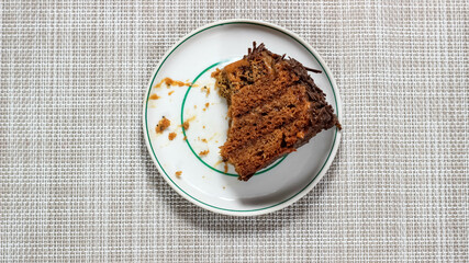 A piece of half-eaten chocolate cake on a saucer.