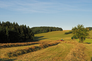 Fototapeta premium Agricultural machine during work on a small foothill meadow