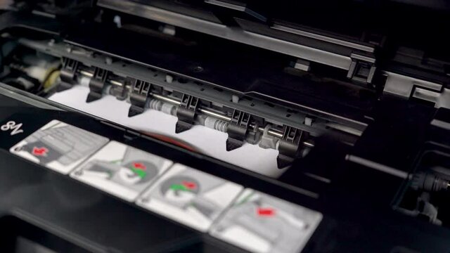 The printhead of the inkjet printer is working. and is printing something on white paper.
