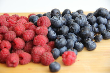 blueberries and raspberries on wooden background