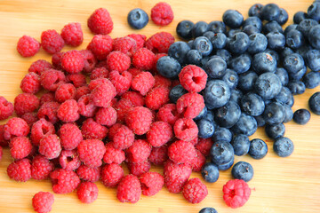 raspberries and blueberries on wooden table