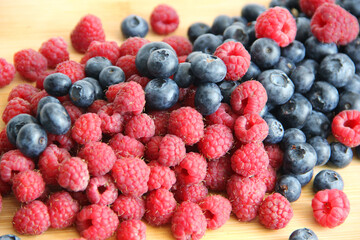 raspberries and blueberries on wooden table