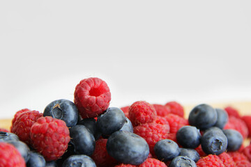 fresh raspberries and blueberries on a white background close-up