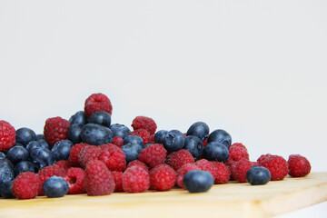 fresh raspberries and blueberries on a white background close-up