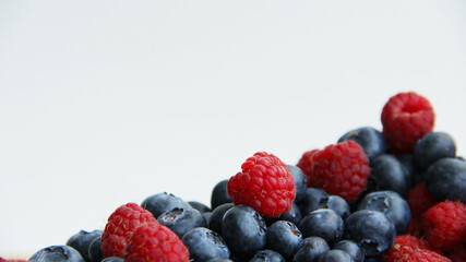 fresh raspberries and blueberries on a white background close-up
