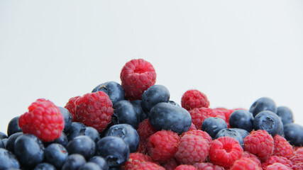 fresh raspberries and blueberries on a white background close-up