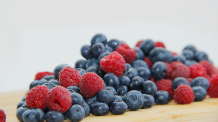 fresh raspberries and blueberries on a white background close-up