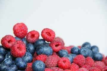 fresh raspberries and blueberries on a white background close-up