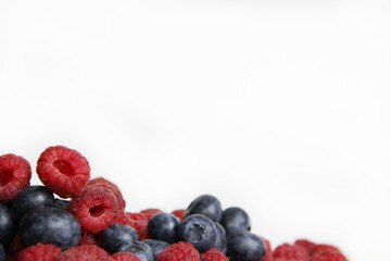 fresh raspberries and blueberries on a white background close-up