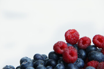 fresh raspberries and blueberries on a white background close-up