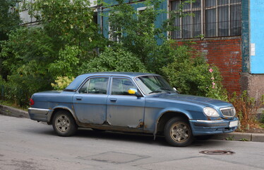 Fototapeta na wymiar An old blue Soviet car in the courtyard of a residential building, Podvoysky Street, St. Petersburg, Russia, July 2021