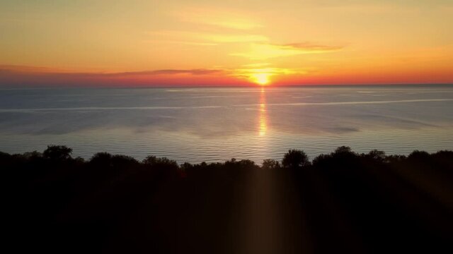 Landscape of the sunset over the ocean next to the precipice filmed by drone. Aerial footage of the dusk over the Baltic sea near the cliff on the warm summer evening. Spending holidays on a shoreline