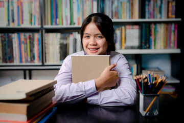 Teenage girl student in school uniform sitting in the library reading a book.