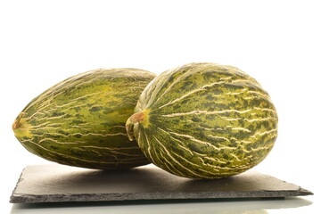 Two ripe organic melons on a slate stone, close-up, isolated on white.