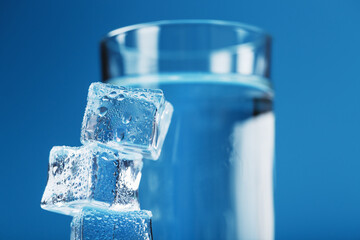 A glass of ice and clear water, ice cubes on a blue background.