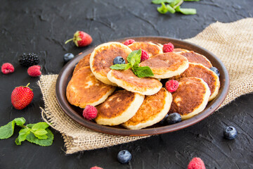 A healthy breakfast of cheese pancakes, berries, and honey. Creative atmospheric decoration