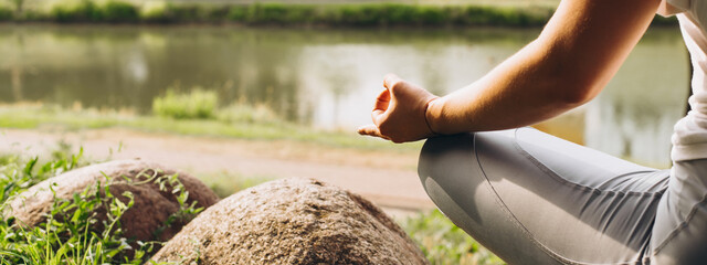 Outdoor meditation, banner, copy space. Close-up of a meditating young woman sitting in a lotus...