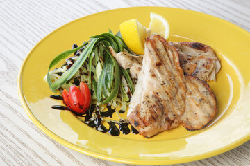 White chicken meat served with arugula on yellow plate