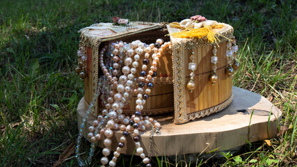 Iridescent pearl necklaces in a lovely handmade wicker jewelry box on the grass. Vintage...