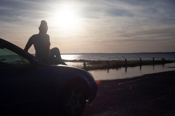 Person sitting on car during sunset