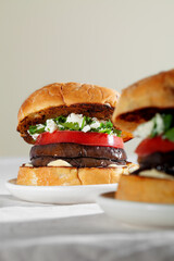 Close up of eggplant sandwich burger with feta cheese and cilantro. Plant based food concept