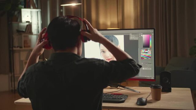 Asian Male Digital Editor Start Works In Photo Editing Software On His Personal Computer With Big Display, He Works At Night 
