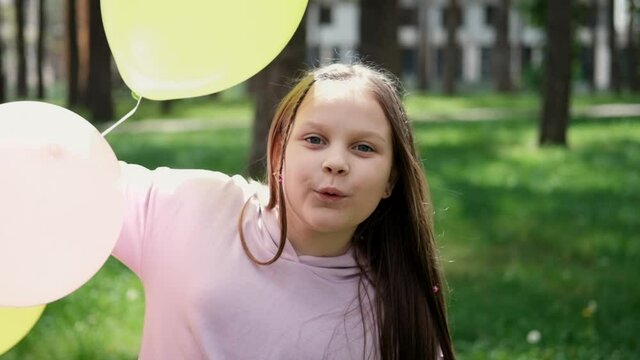 pretty girl tween teenager in purple costume having fun playing with hot air balloons outdoors. holliday, party, birthday, celebration. happy children. slow motion.